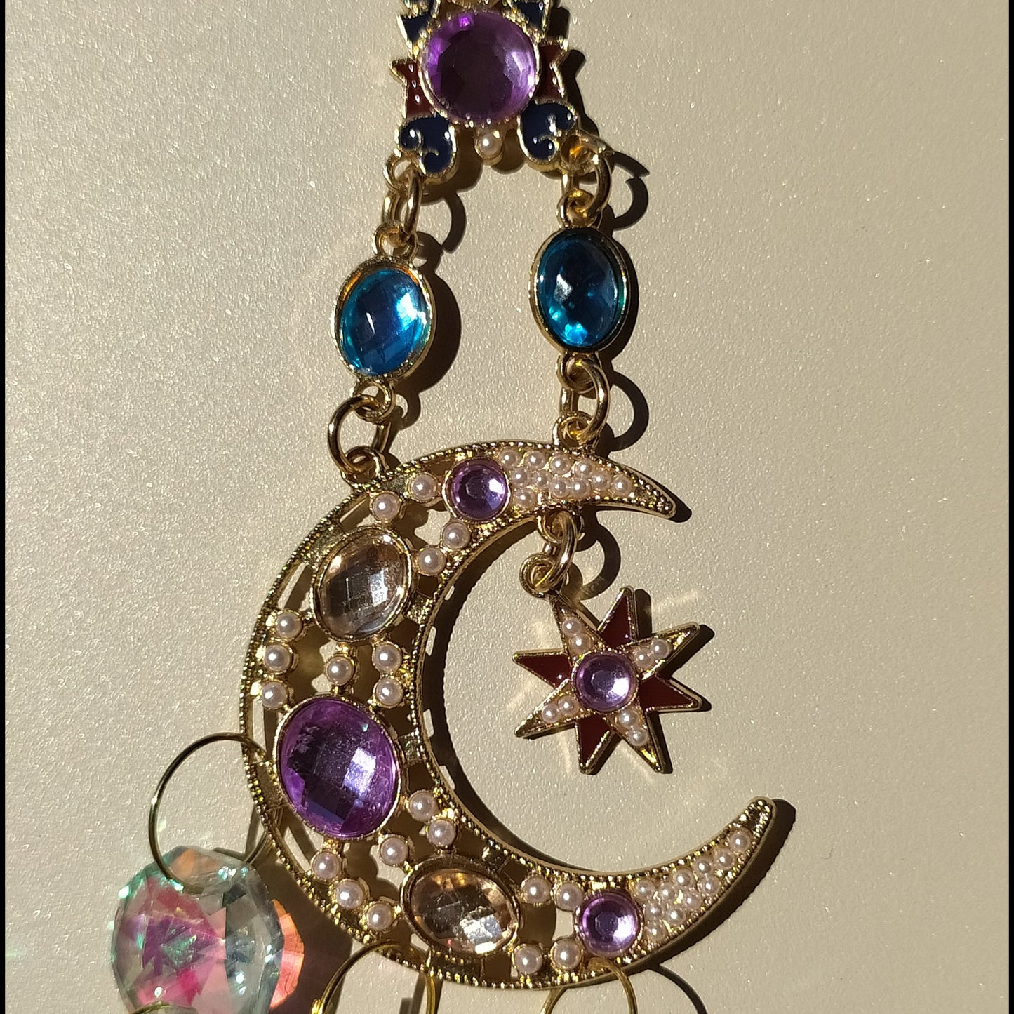 Attrape-soleil Shéhérazade One2K – gros plan sur la lune dorée ornée de perles nacrées, gemmes violet et bleu saphir avec pendentif cristal K9 effet AB irisé