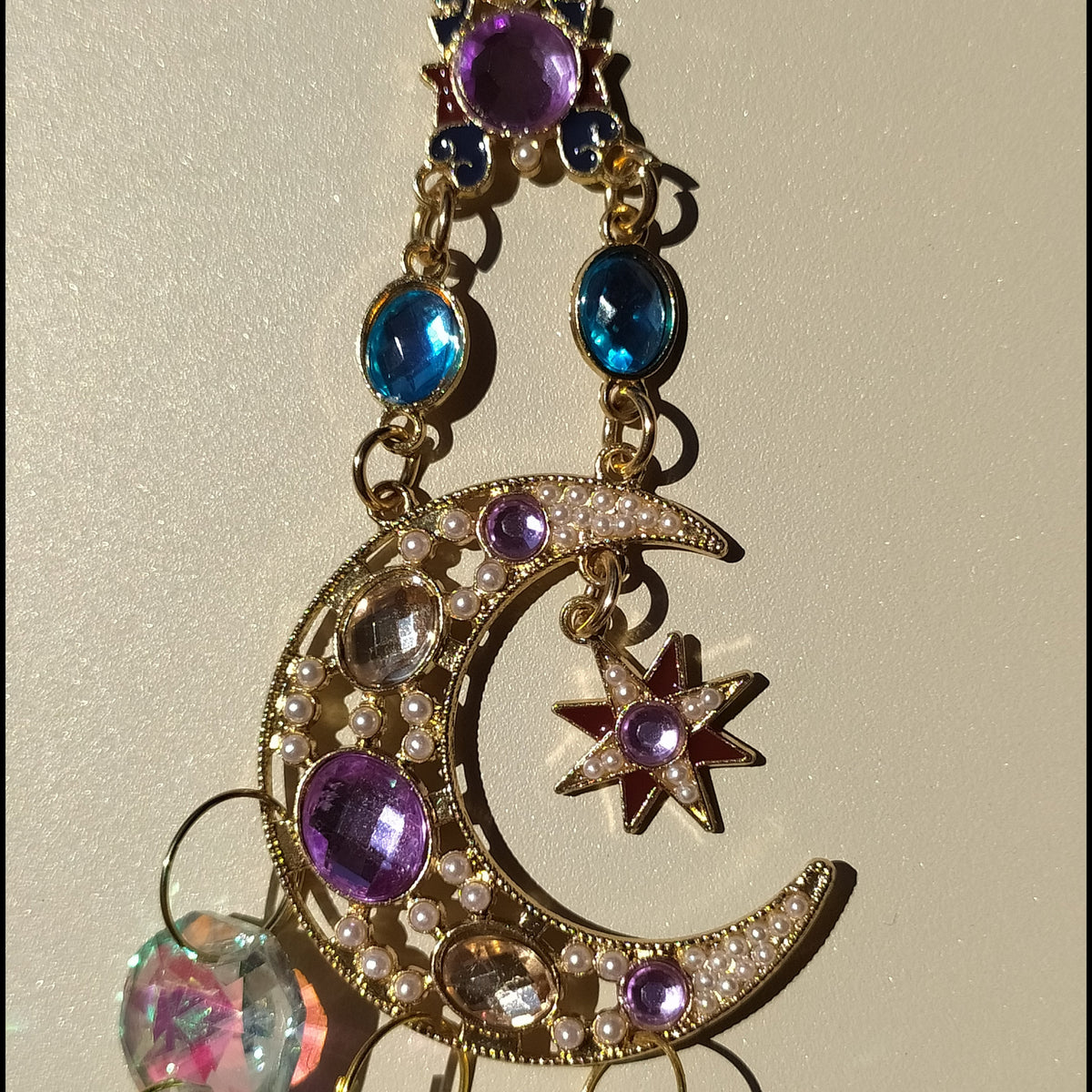 Attrape-soleil Shéhérazade One2K – gros plan sur la lune dorée ornée de perles nacrées, gemmes violet et bleu saphir avec pendentif cristal K9 effet AB irisé
