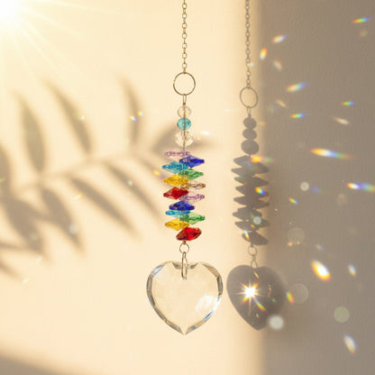 Attrape-soleil Sissi One2K – spirale de cristaux K9 multicolores chakra avec pendentif cœur en cristal K9 transparent, reflets arc-en-ciel sur fond sable doré
