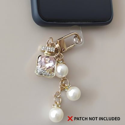 Bijou de sac téléphone 3-en-1 Élixir Rose One2K – situation d'usage accroché à un smartphone noir sur fond beige, flacon cristal rose LOVE et perles nacrées, patch non inclus
