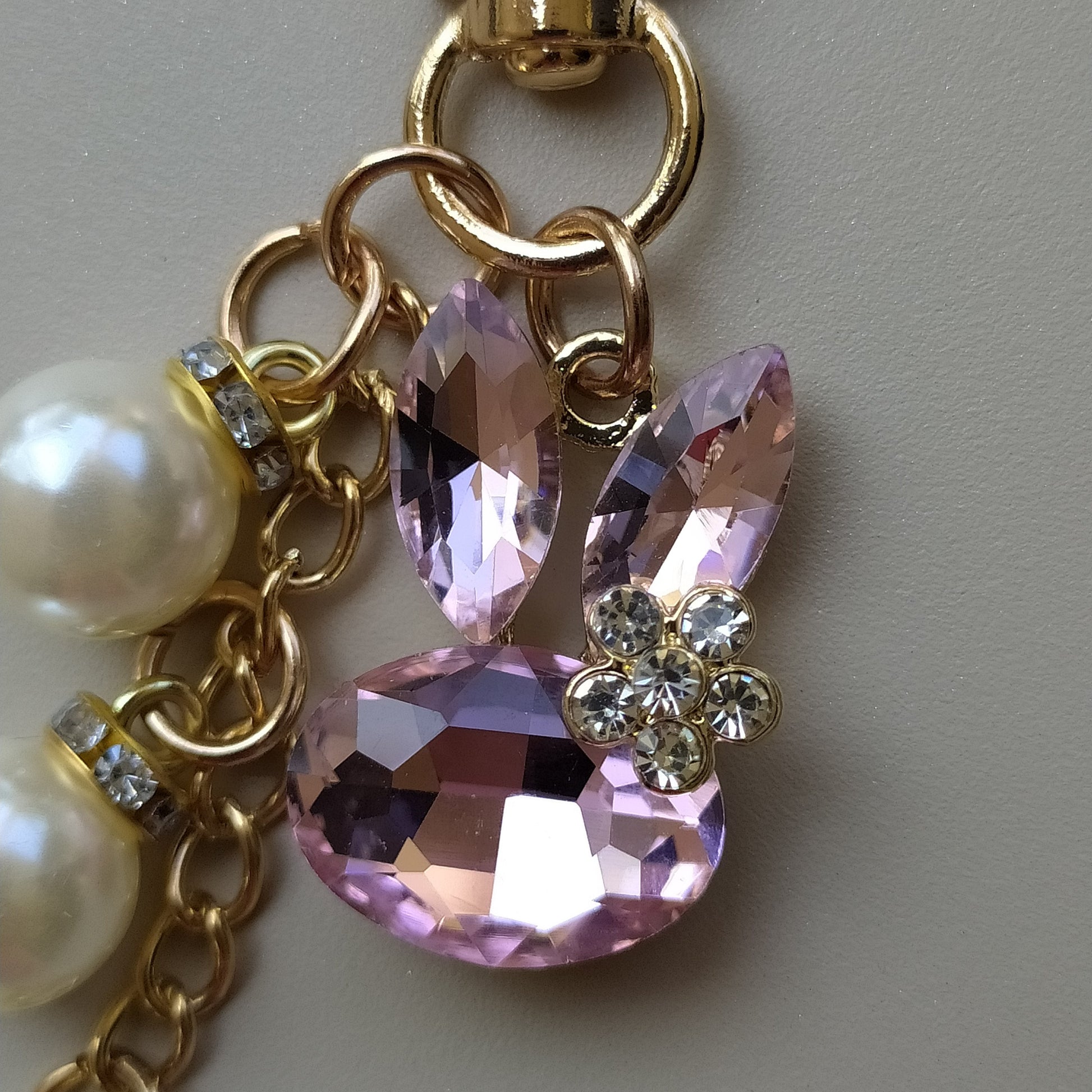 Bijou de sac téléphone 3-en-1 Lapin de Cristal One2K – gros plan sur le lapin formé de cristaux rose taille marquise et ovale avec strass transparents en fleur et perles nacrées sur chaîne dorée