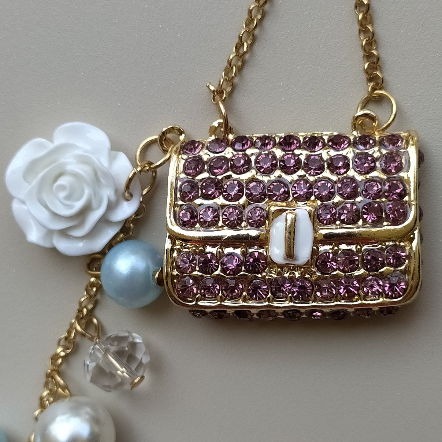 Bijou de sac téléphone 3-en-1 Mini Sac Pourpre One2K – gros plan sur le mini sac recouvert de strass pourpres, rose blanche en nacre et perle bleue