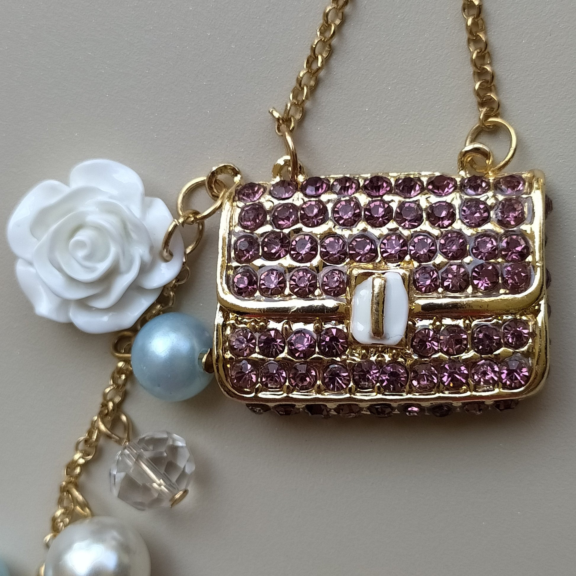 Bijou de sac téléphone 3-en-1 Mini Sac Pourpre One2K – gros plan sur le mini sac recouvert de strass pourpres, rose blanche en nacre et perle bleue