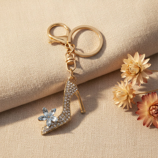 Bijou de sac téléphone 3-en-1 Soulier de Cristal One2K – photo ambiance sur tissu beige avec fleurs séchées crème et terracotta, escarpin strass doré et fleur cristal 

