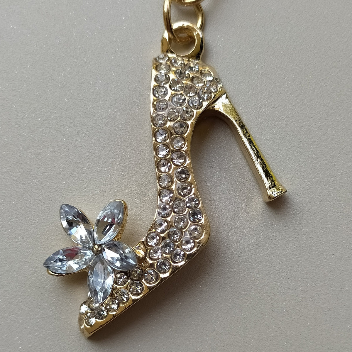 Bijou de sac téléphone 3-en-1 Soulier de Cristal One2K – gros plan sur l'escarpin serti de strass ronds dorés et fleur en cristaux taille marquise