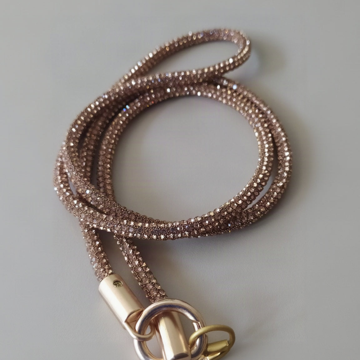 Collier téléphone infini strass One2K version or – gros plan sur la corde tubulaire entièrement recouverte de micro-strass dorés champagne scintillants, fermoir cylindrique doré et anneau ressort doré
