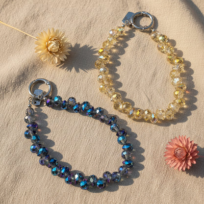Bijou 2-en-1 Dragonne de Poignet & Bijou de Sac Éclat Boréal One2K – vue présentation des deux variantes reflets azur et reflets solaires sur tissu lin avec fleurs séchées, perles de cristal facettées aux reflets irisés dorés et transparents, fermoir anneau argenté
