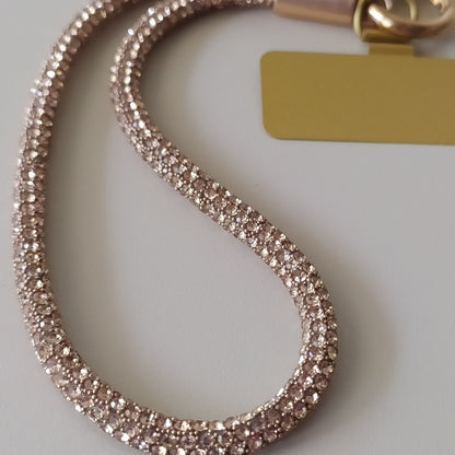 Dragonne poignet téléphone infini strass One2K version or – gros plan sur la corde tubulaire entièrement recouverte de micro-strass dorés champagne scintillants, fermoir cylindrique doré et patch rectangulaire doré
