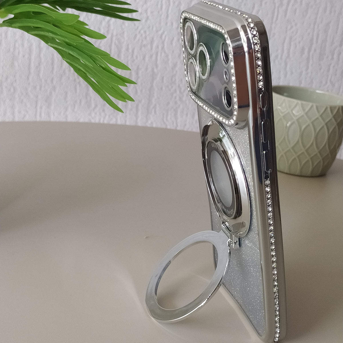 Coque iPhone 17 Pro Cristal Chic argent One2K –  présentation sur une table avec l'anneau support - photo lifestyle


