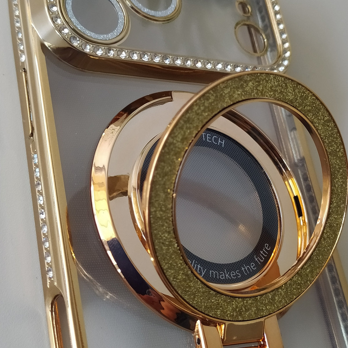 Coque iPhone 17 Pro Cristal Chic or One2K – gros plan détail cristal et anneau support or scintillant

