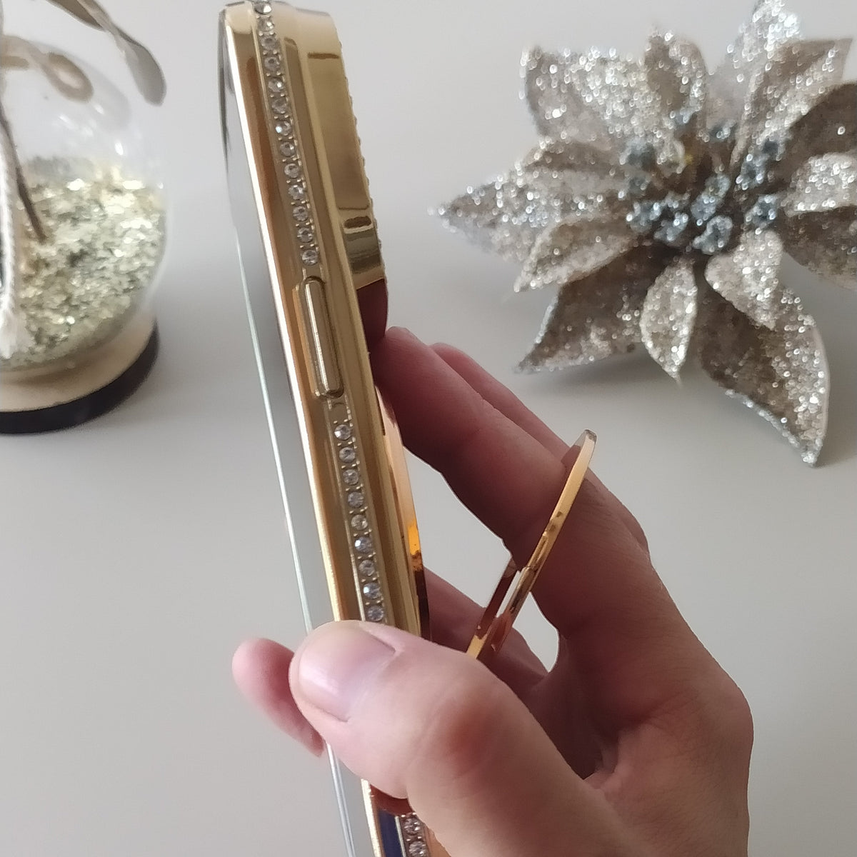 Coque iPhone 17 Pro Max Cristal Chic Or Solaire One2K – prise en main avec l'anneau support, photo lifestyle, accessoire de mode élégant au quotidien
